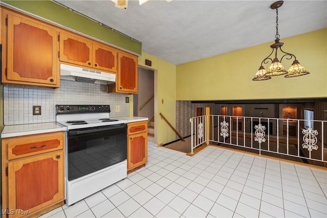 kitchen with backsplash, under cabinet range hood, a chandelier, light countertops, and electric range oven