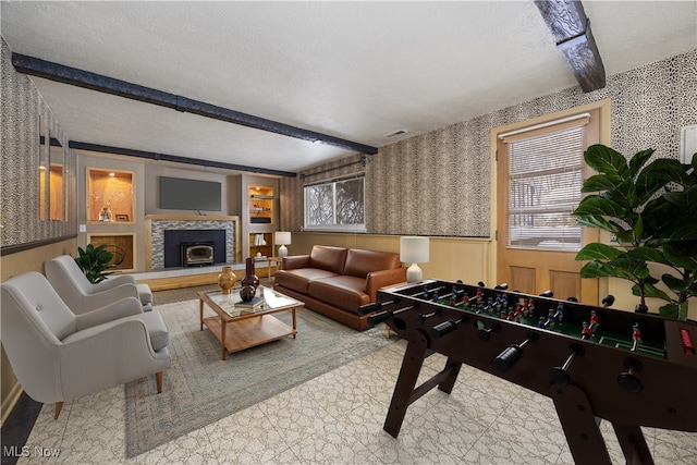 living room featuring wallpapered walls, beam ceiling, a textured ceiling, and wainscoting