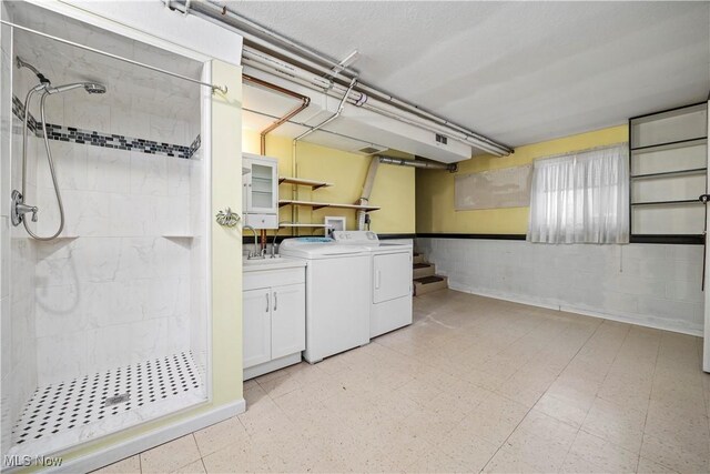 laundry room with cabinet space, washer and dryer, light floors, and a sink