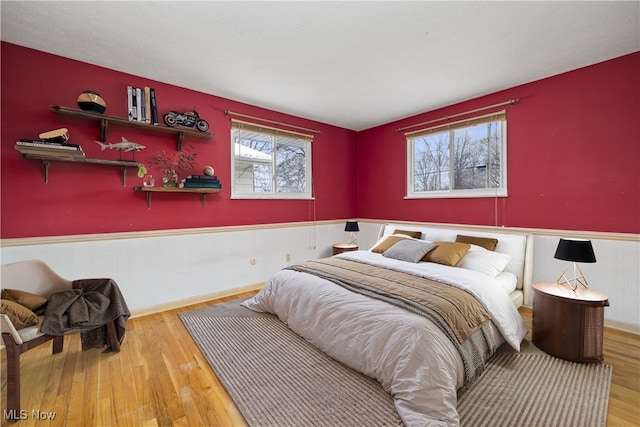 bedroom with wood finished floors and wainscoting