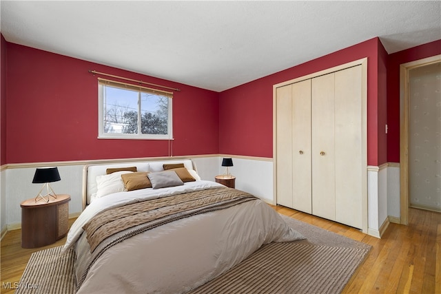 bedroom featuring a closet, wainscoting, and wood-type flooring