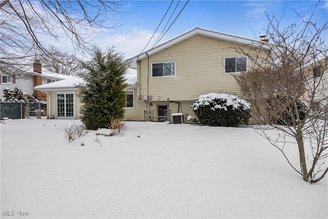 snow covered rear of property with central AC unit and fence