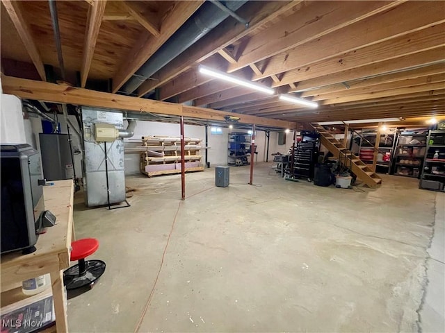 unfinished basement featuring stairs, heating unit, and water heater