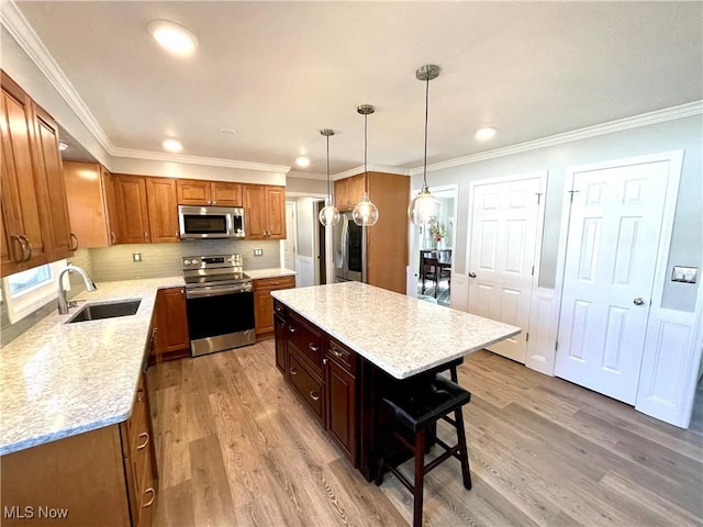 kitchen featuring light wood-style flooring, appliances with stainless steel finishes, a breakfast bar area, and a sink