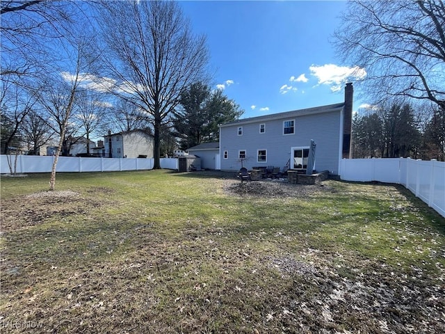 rear view of house with a yard, a fenced backyard, and a chimney