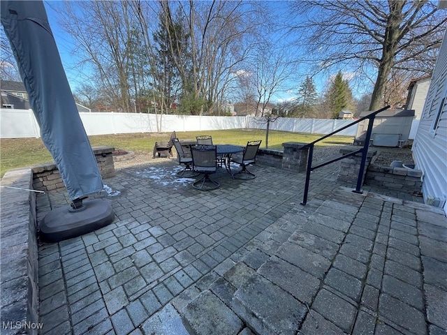 view of patio featuring outdoor dining space, an outbuilding, and a fenced backyard