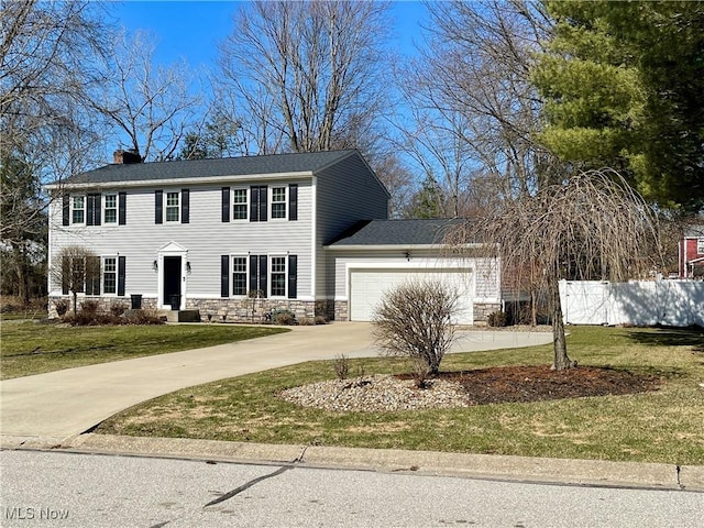 colonial home with stone siding, fence, concrete driveway, a front yard, and a garage