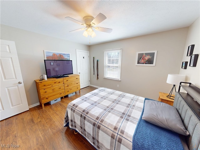 bedroom featuring baseboards, wood finished floors, and a ceiling fan