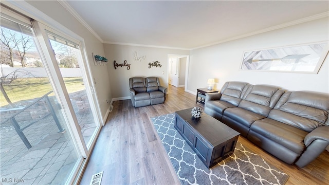 living area with baseboards, wood finished floors, visible vents, and ornamental molding