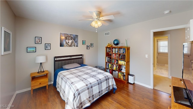 bedroom featuring visible vents, a ceiling fan, baseboards, and wood finished floors