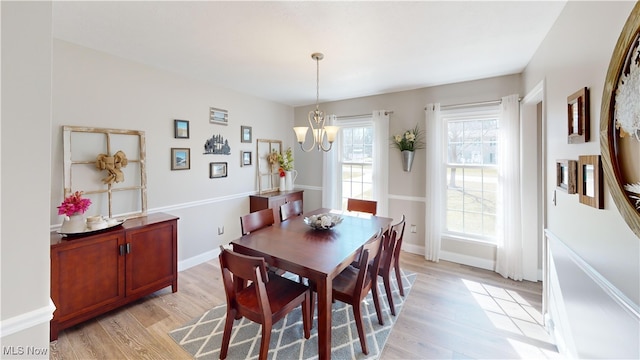 dining room featuring baseboards, a notable chandelier, and light wood-style flooring