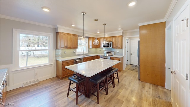 kitchen featuring light wood-type flooring, visible vents, a kitchen breakfast bar, and appliances with stainless steel finishes