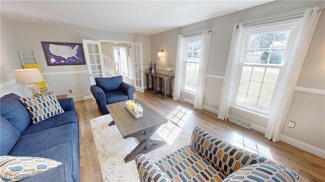 living area featuring visible vents, baseboards, and wood finished floors