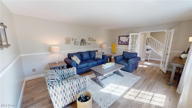 living room with stairway, french doors, baseboards, and wood finished floors