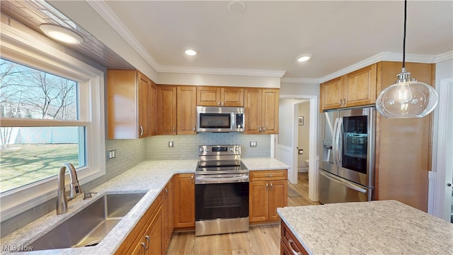 kitchen featuring light wood-style flooring, ornamental molding, a sink, backsplash, and appliances with stainless steel finishes