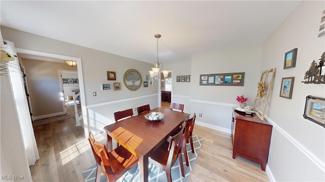 dining room featuring baseboards, light wood-type flooring, and a chandelier