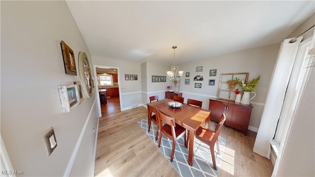 dining space with baseboards, light wood-style floors, and an inviting chandelier