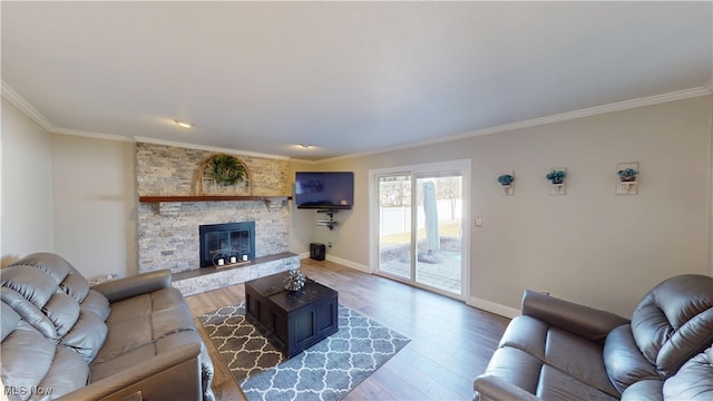 living room featuring light wood-style flooring, a fireplace, crown molding, and baseboards