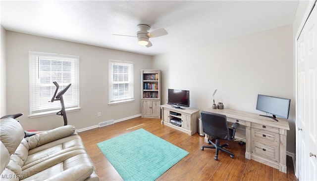 office area with visible vents, baseboards, light wood-style floors, and a ceiling fan