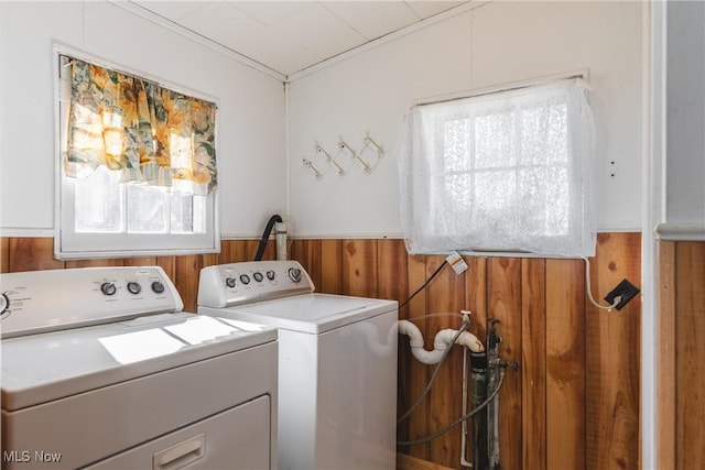 washroom featuring a wainscoted wall, washing machine and dryer, laundry area, and wood walls