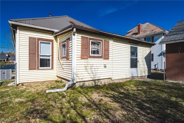 view of side of property with metal roof, a yard, cooling unit, and fence