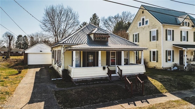 view of front of home with an outbuilding, a standing seam roof, covered porch, a detached garage, and metal roof