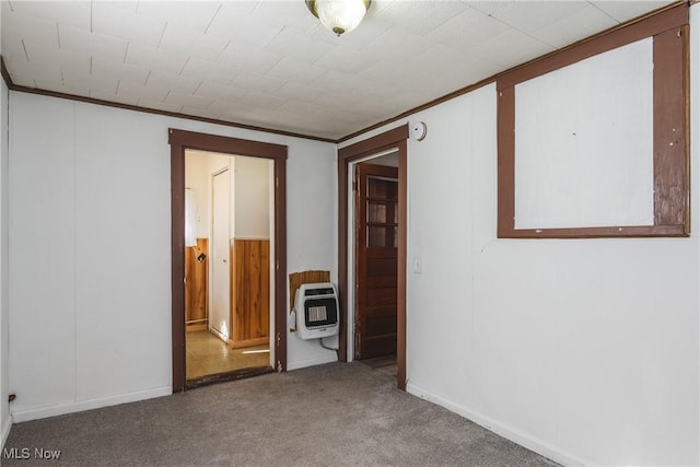 spare room with heating unit, ornamental molding, and carpet flooring