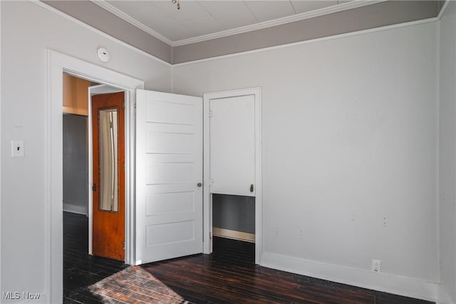 empty room with crown molding, dark wood-type flooring, and baseboards