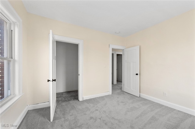 unfurnished bedroom featuring multiple windows, baseboards, and carpet