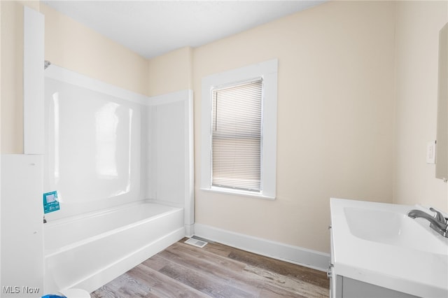 bathroom with vanity, wood finished floors, visible vents, baseboards, and shower / tub combination