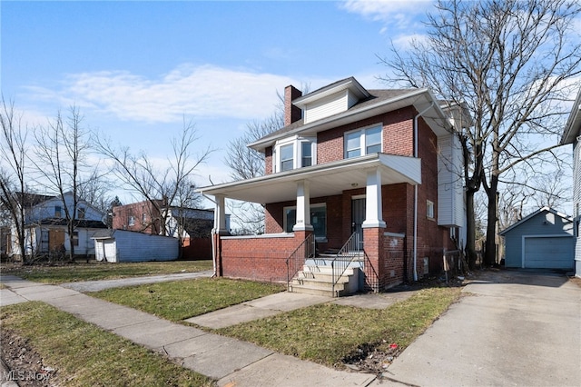 traditional style home featuring a porch, an outdoor structure, a garage, aphalt driveway, and brick siding