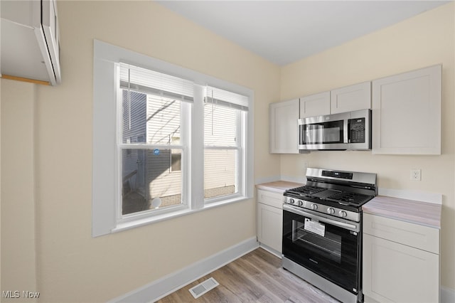 kitchen with visible vents, baseboards, light countertops, light wood-style floors, and stainless steel appliances