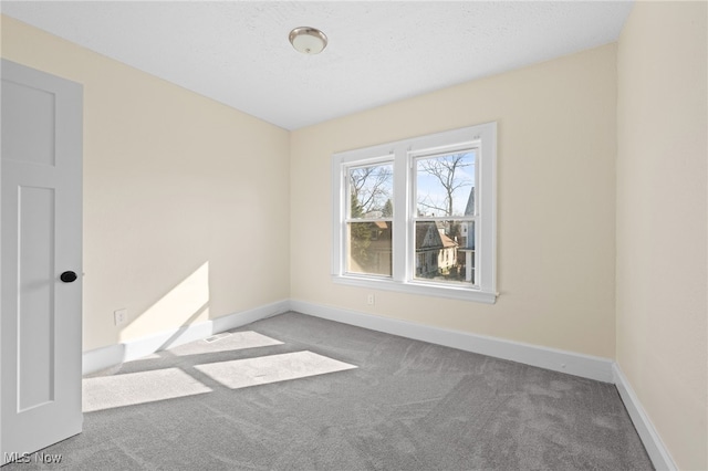 unfurnished room featuring carpet flooring, a textured ceiling, and baseboards