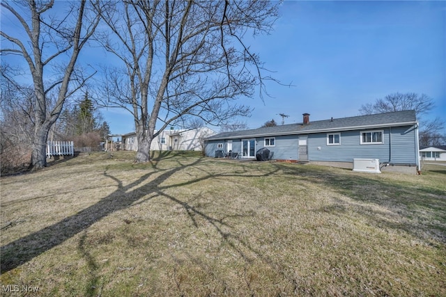 rear view of house featuring a lawn, fence, and a chimney