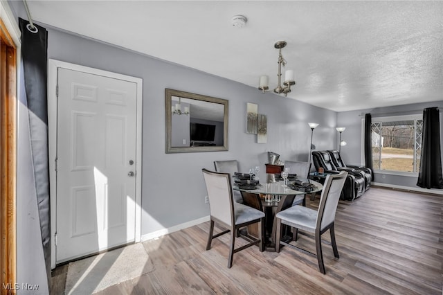 dining room featuring an inviting chandelier, wood finished floors, baseboards, and a textured ceiling