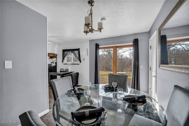 dining room with baseboards, a textured ceiling, an inviting chandelier, and wood finished floors