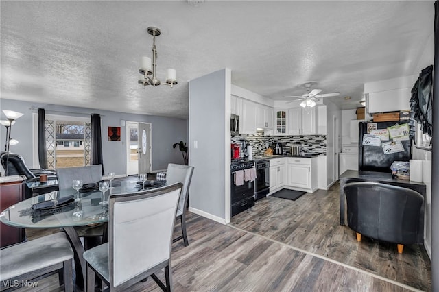 dining area featuring baseboards, a textured ceiling, dark wood finished floors, and ceiling fan with notable chandelier