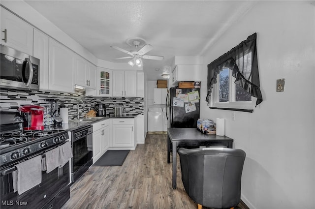 kitchen featuring backsplash, white cabinetry, black appliances, and a sink