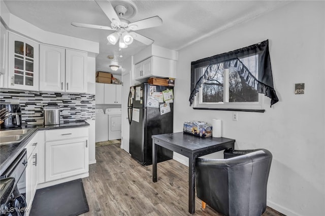 kitchen with light wood finished floors, freestanding refrigerator, white cabinets, dark countertops, and independent washer and dryer