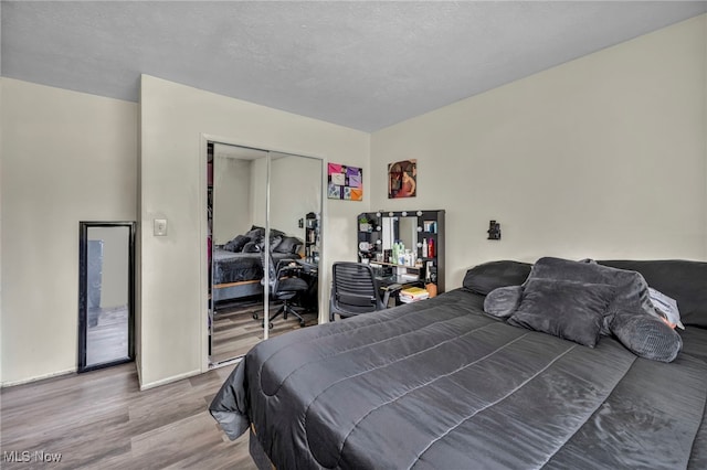 bedroom with baseboards, wood finished floors, a closet, and a textured ceiling