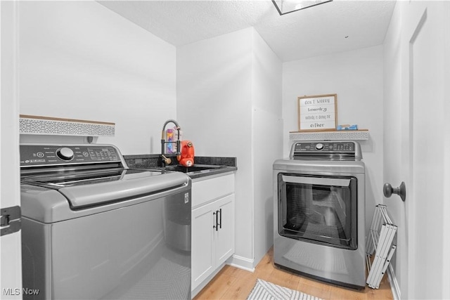 washroom featuring a sink, cabinet space, light wood-style floors, and washing machine and dryer