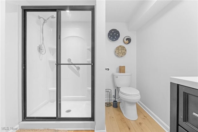 bathroom featuring a shower stall, baseboards, toilet, wood finished floors, and vanity