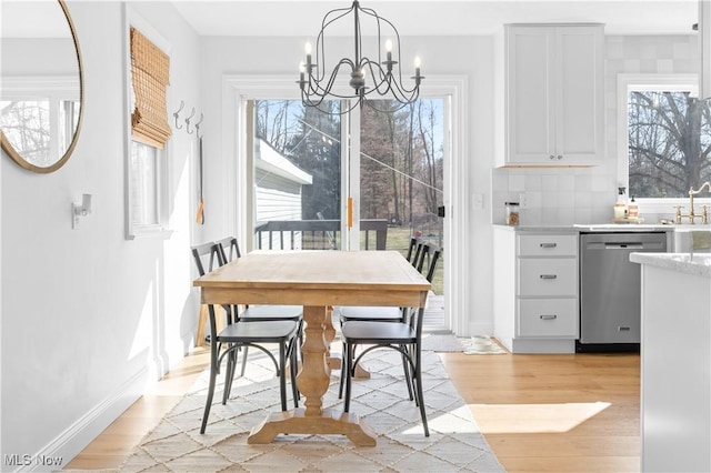 dining area with a notable chandelier, baseboards, and light wood-style floors