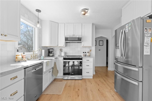 kitchen with white cabinetry, arched walkways, and stainless steel appliances