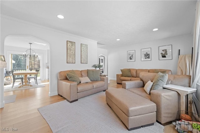 living area with recessed lighting, arched walkways, ornamental molding, a notable chandelier, and light wood-type flooring