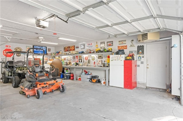 garage with a workshop area, a garage door opener, and freestanding refrigerator