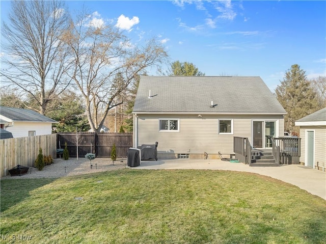 rear view of house featuring fence, a wooden deck, a yard, a shingled roof, and a patio area