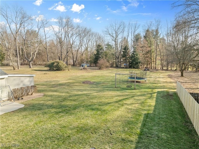 view of yard featuring a trampoline and fence