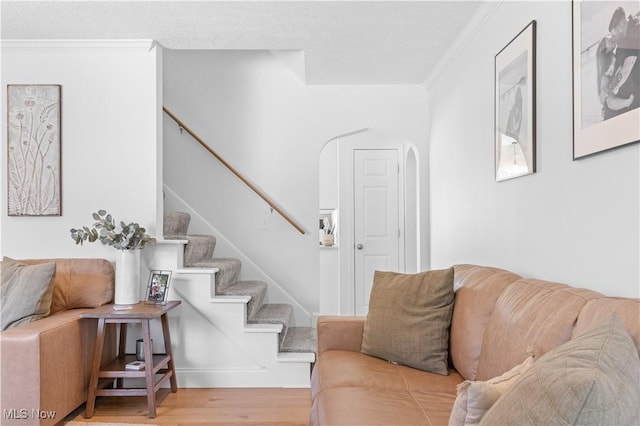 living area with stairs, wood finished floors, arched walkways, and ornamental molding