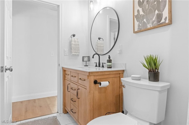 half bath featuring vanity, toilet, and baseboards